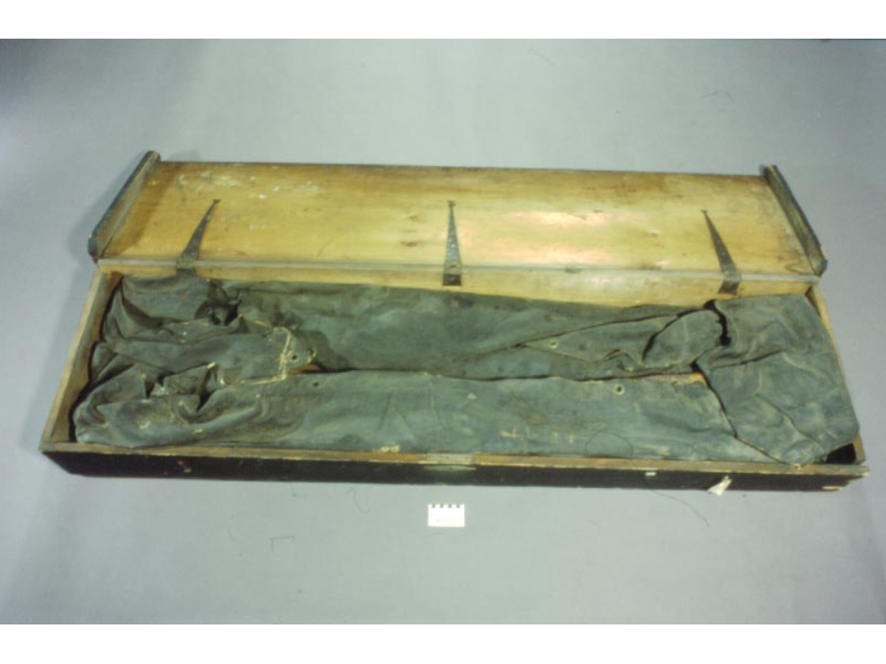 A deflated and folded boat in a rectangular chipping case with the hinged lid open.