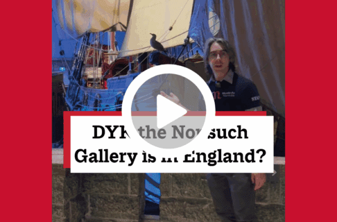 A screenshot of a video, an individual stands in the Nonsuch Gallery in front of a large sailing vessel. There's a play button over the screenshot and overlaid text reads, "DYK the Nonsuch Gallery is in England?".