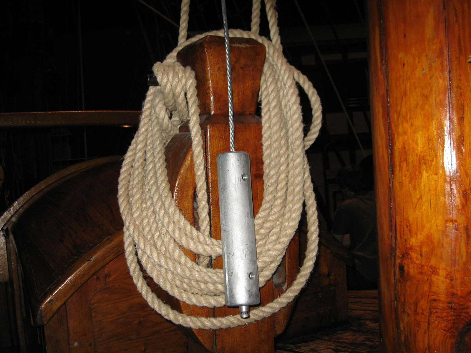 A coil of cream rope on a wooden notch. In the front there's a steel safety line.