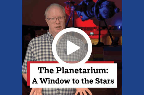 A screenshot of a video, an individual stands in the doorway of the Planetarium, the Zeiss projector lit with blue and red behind them. There's a play button over the screenshot and overlaid text reads, "The Planetarium: A Window to the Stars".