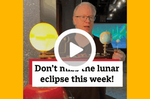 A screenshot of a video, an individual stands in the Science Gallery behind a model of the Sun, Earth, and Moon. There's a play button over the screenshot and overlaid text reads, "Don't miss the lunar eclipse this week!".