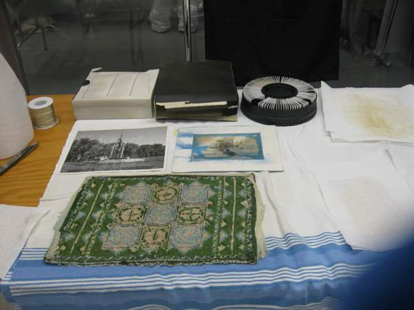 A small tapestry and two prints laid out on a cotton sheet.