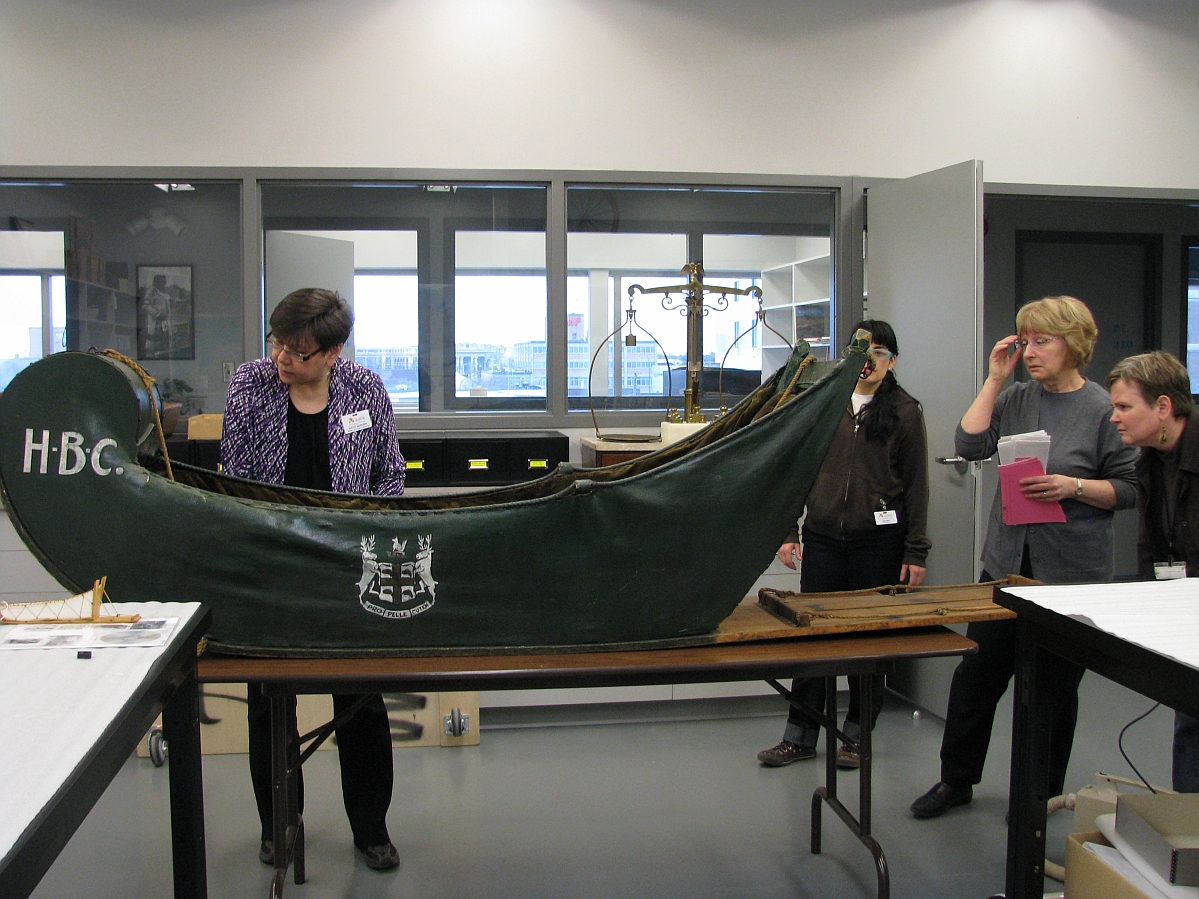 Four individuals standing around a cariole sledge on a table in a museum lab.