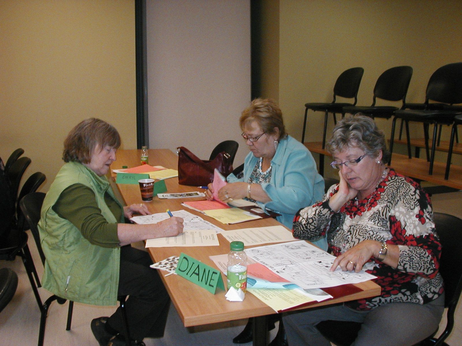 Three individuals seated around a table in discussion with each other over papers and notebooks.