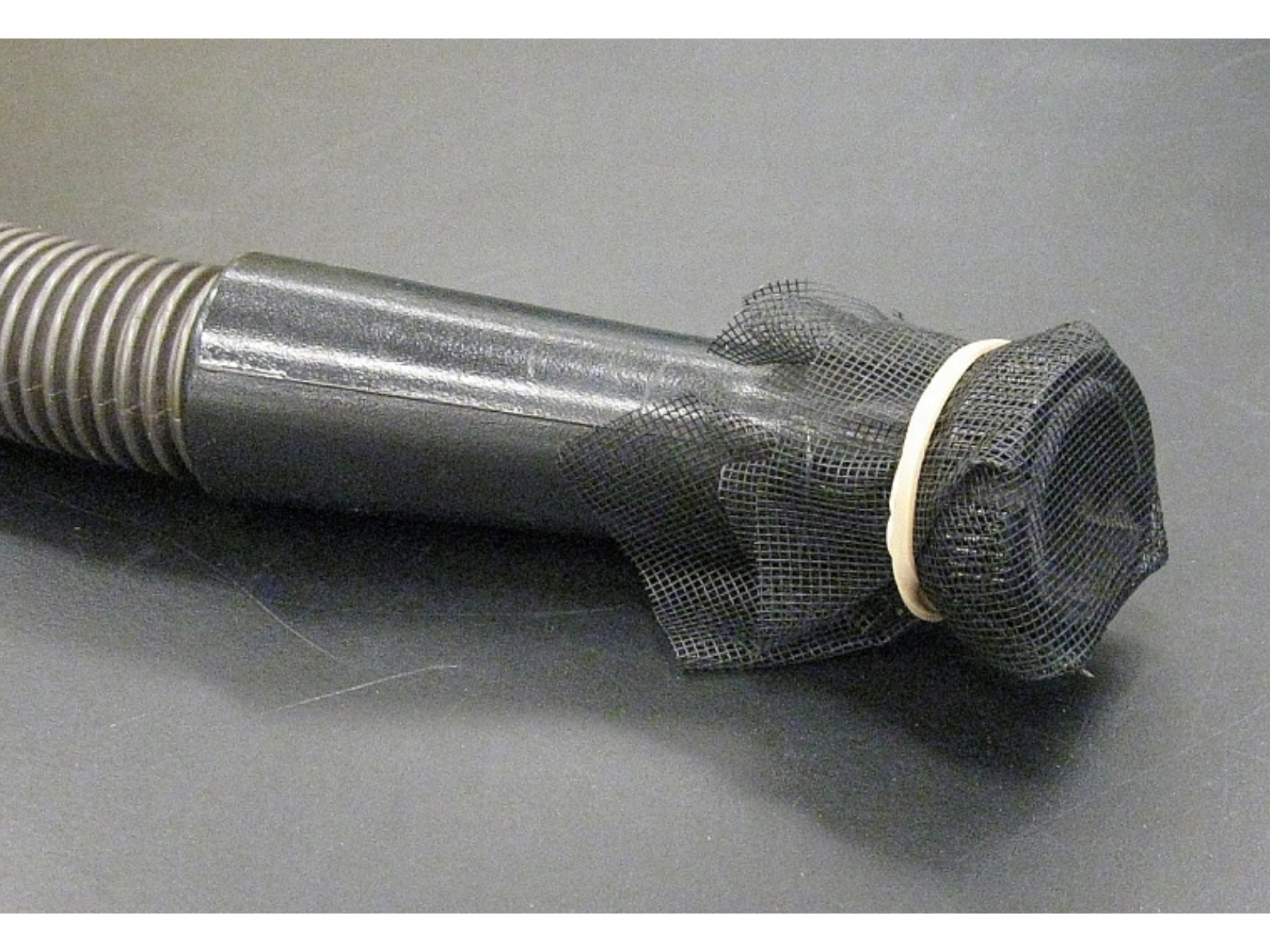 Close-up on the nozzle of a vacuum cleaner with screening held over it with an elastic band.