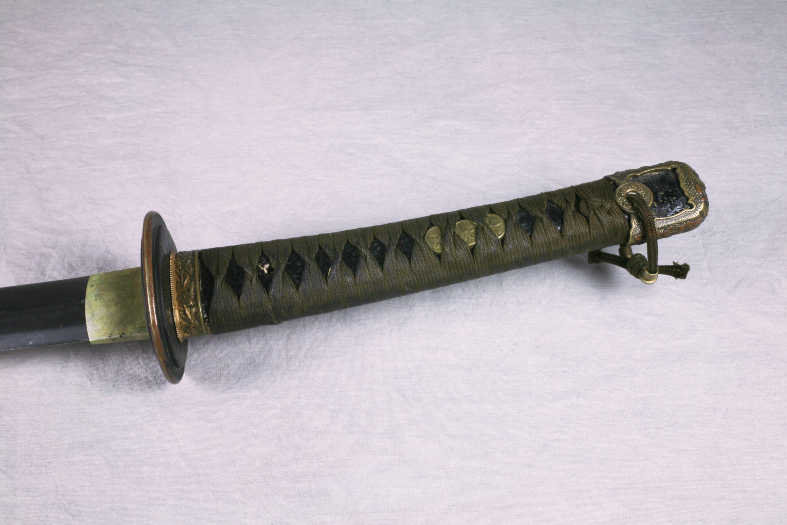Close up on the hilt and handle of an old Japanese-style military sword.