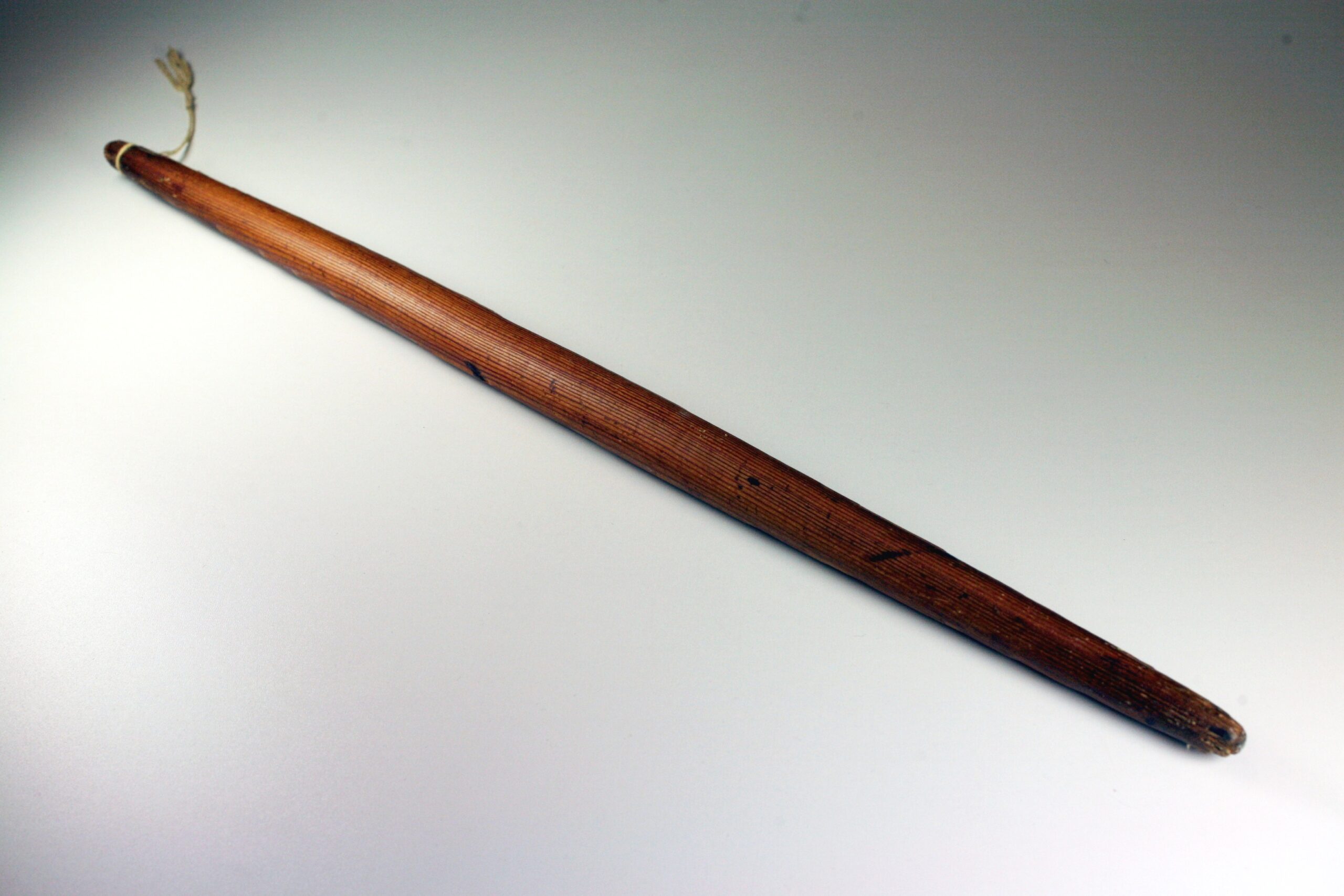 A rolling pin made from a single piece of wood, fashioned into a two-foot long rod tapered at both ends.