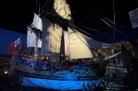 Photograph of a large wooden ship (the Nonsuch) with her sails out “in dock” in the Nonsuch Gallery of the Manitoba Museum.