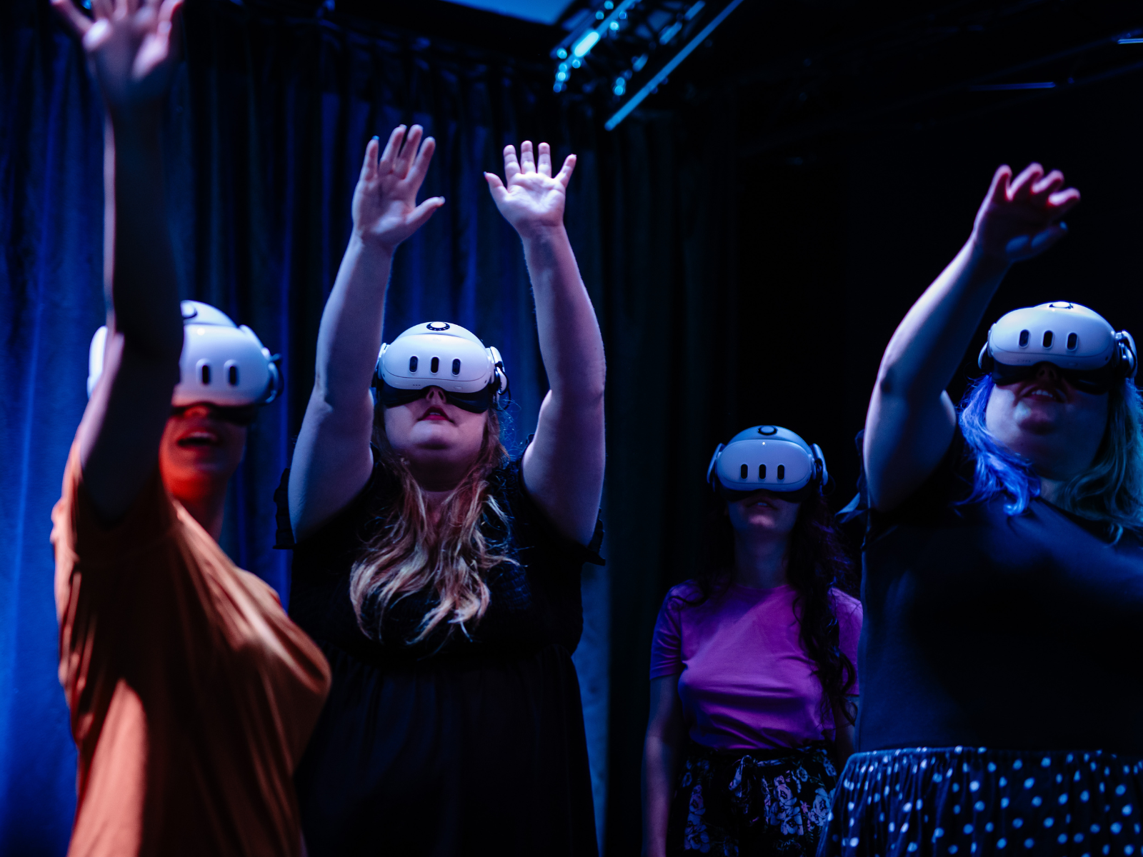 Four individuals wearing AR headsets reaching out to something they're seeing in front of them.