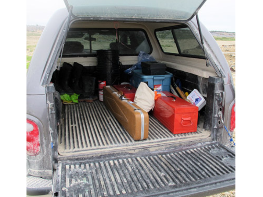 View into the back of a covered pickup truck with neatly placed containers and boxes.