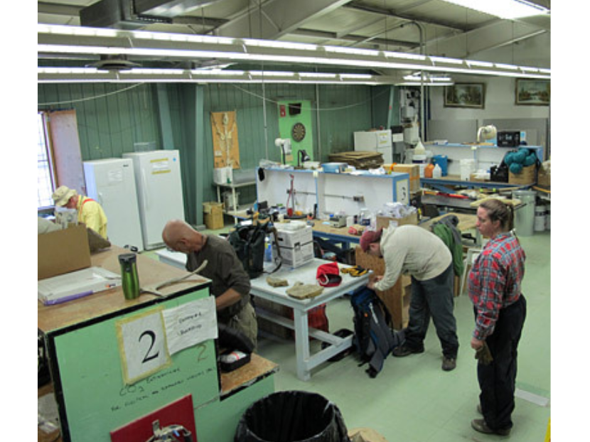 Three individuals standing in a work room/laboratory sorting fossils and specimens.