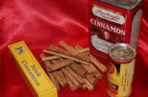 Three containers of various forms of cinnamon on a silky red backdrop accompanied by a small stack of cinnamon sticks.