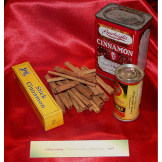 Three containers of various forms of cinnamon on a silky red backdrop accompanied by a small stack of cinnamon sticks.