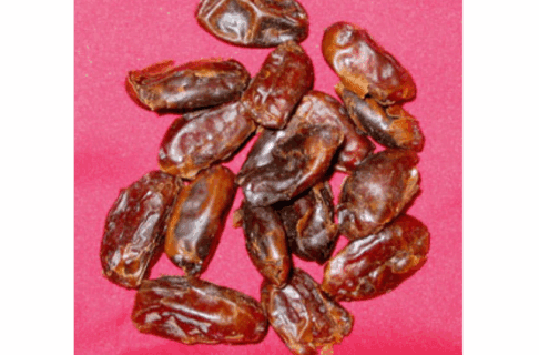 Small pile of dried dates on a red background.