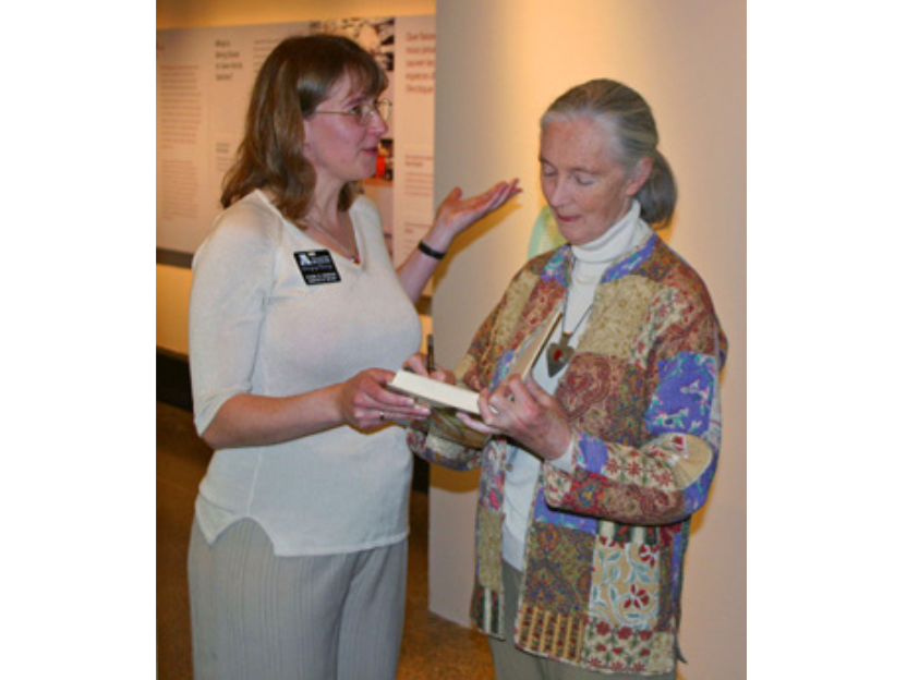 Dr. Diana Bizecki Robson handing a book to Dr. Jane Goodall.