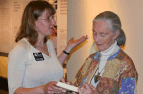 Dr. Diana Bizecki Robson handing a book to Dr. Jane Goodall.