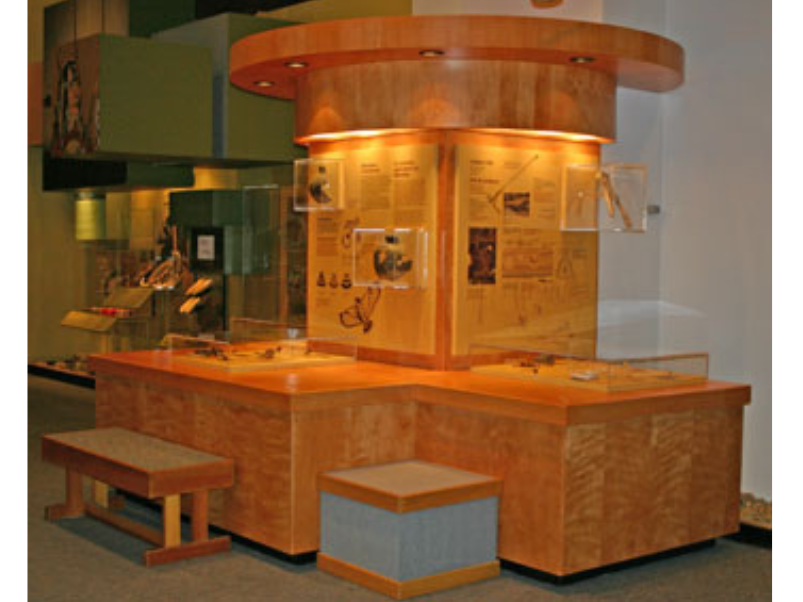 A Museum exhibit  with three sides and benches for seating to engage and read material.