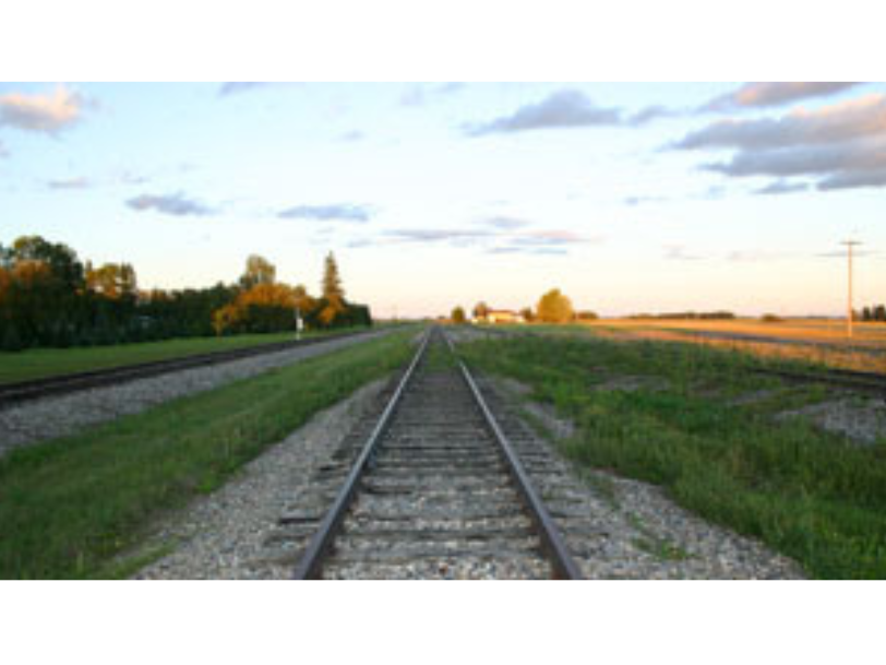 View looking down a set of railroad tracks with grass growing on both sides.