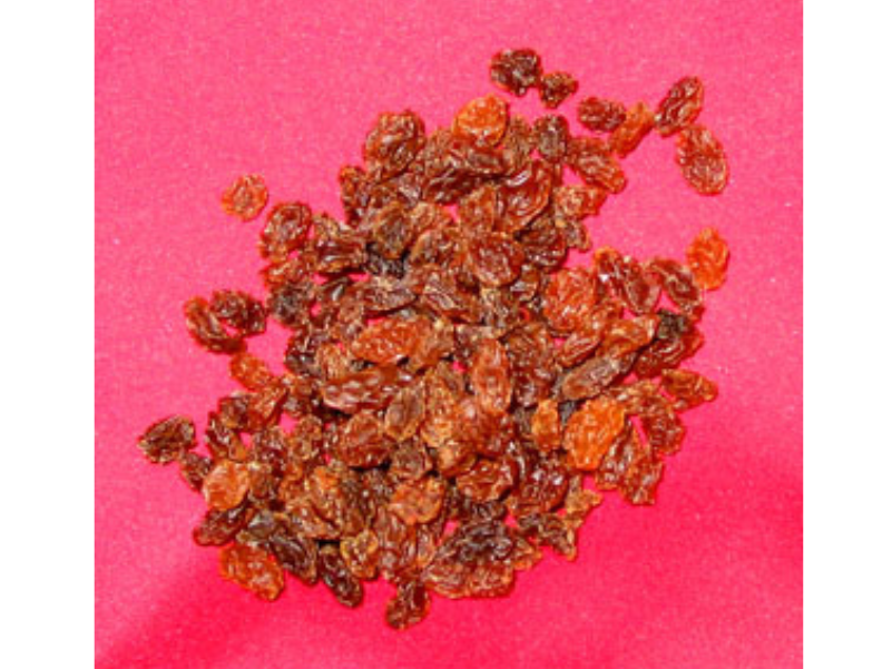 Small pile of dried raisins on a red background.