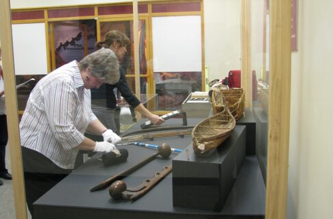 Two individuals placing artifacts into display cases.