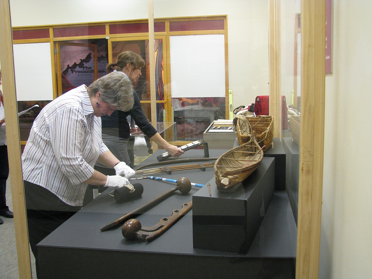 Two individuals placing artifacts into display cases.