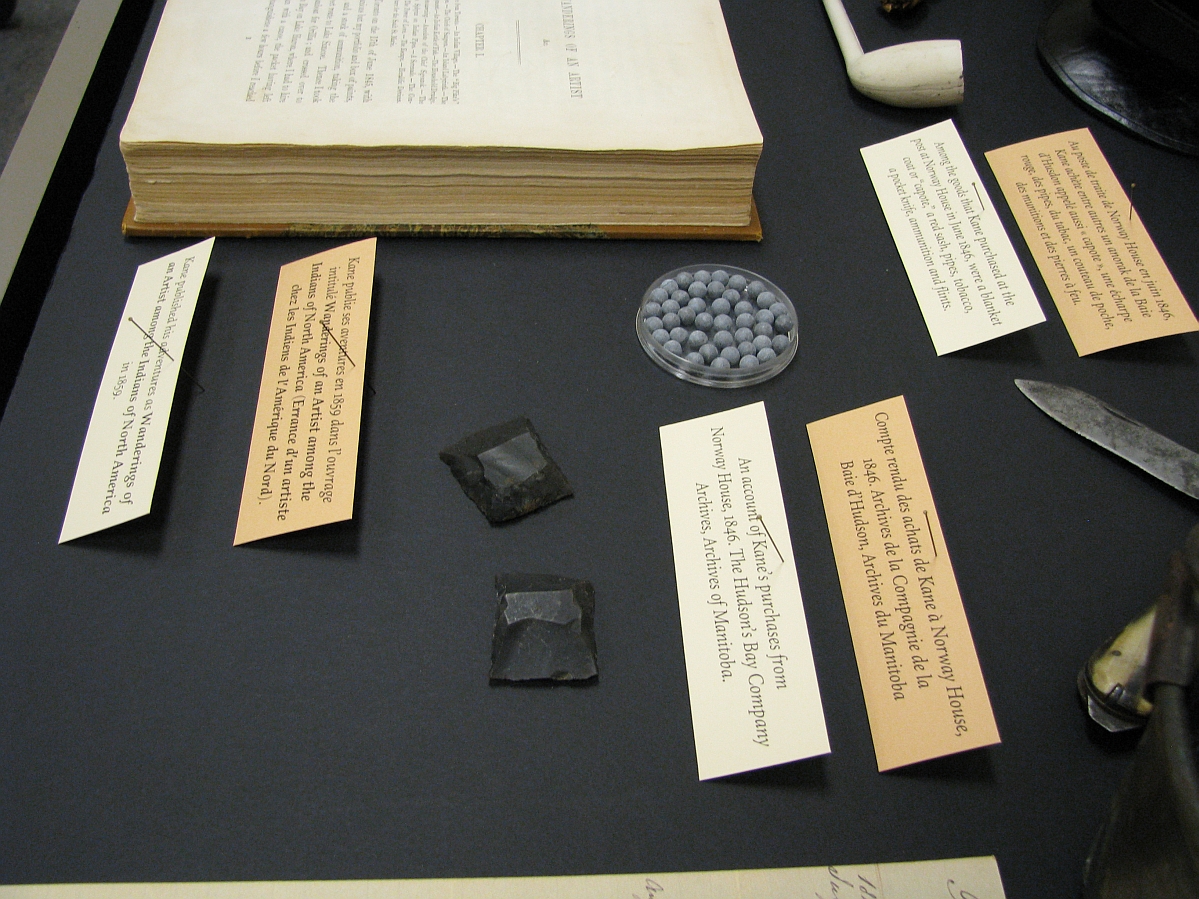 Labels propped up and placed in a display case next to objects.