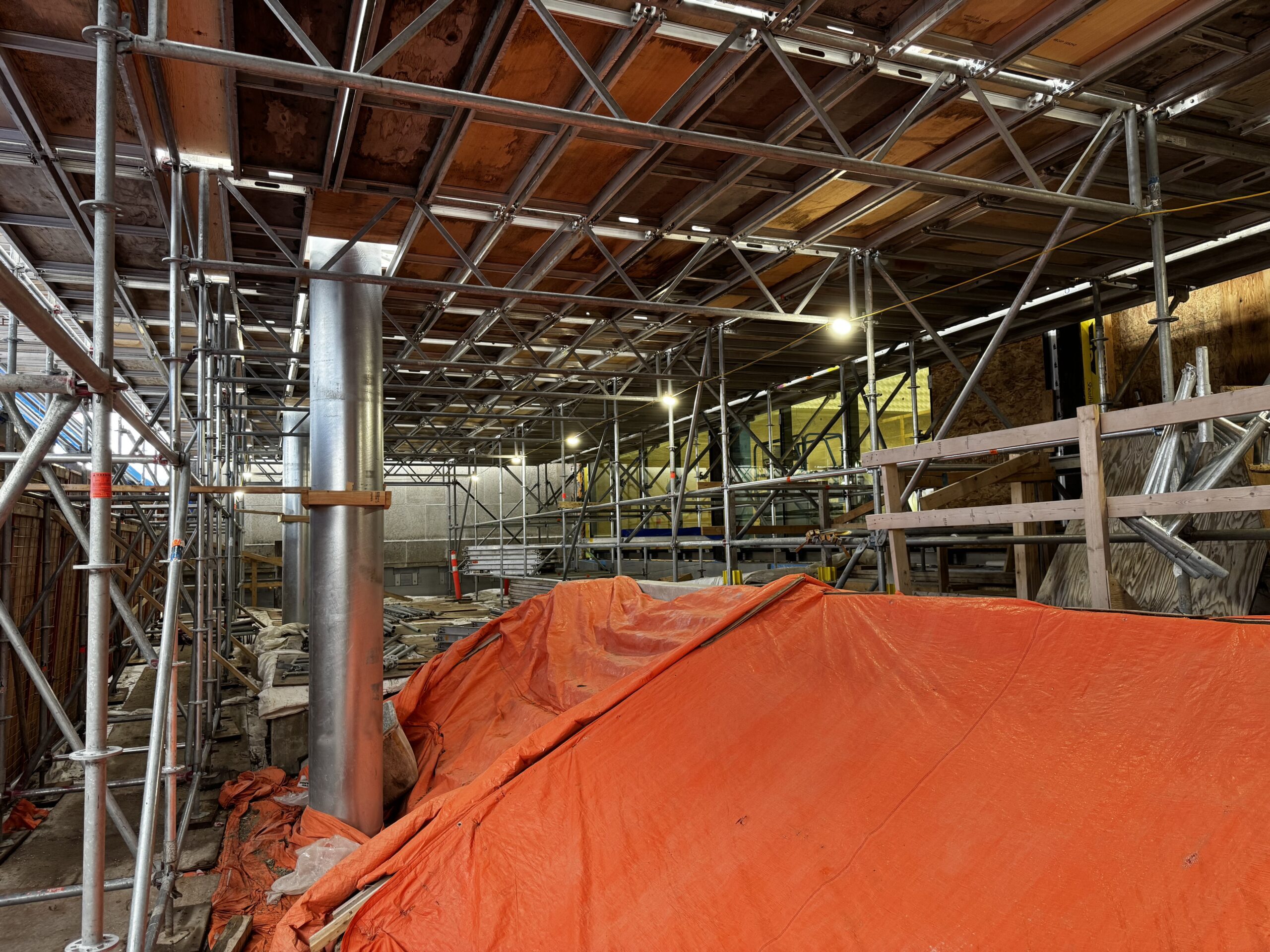 Underneath scaffolding in the Rupert entrance to the Museum. Orange tarpaulins cover the stairwells down to the Concourse level, and scaffolding has been used to create a raised surface for workers to access the new awning.