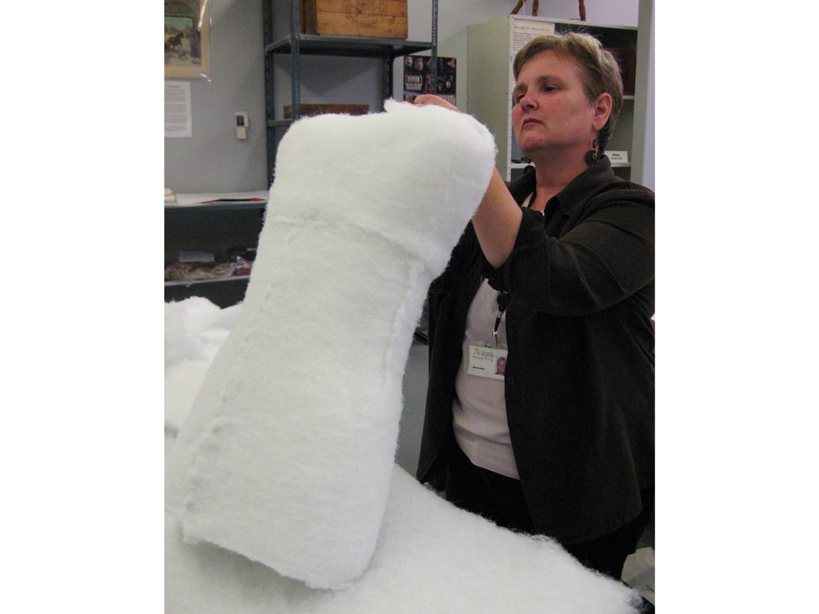 An individual wrapping a carved piece of foam in white cotton batting.