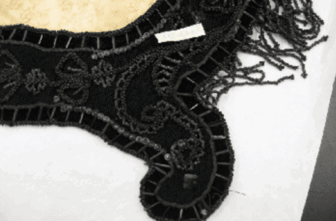 A collar of black velvet with light coloured beads. Some of the beads are a cloudy, whitish colour.