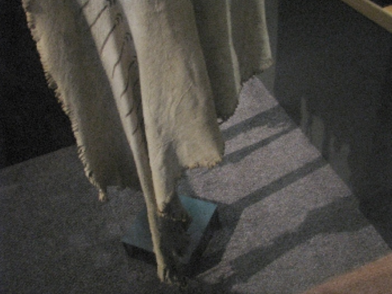 Looking down to the lower section of a dress on a mannequin and the caret below it.