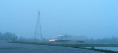 A truck blurred as it drives by across the frame in blue-ish morning low-light.