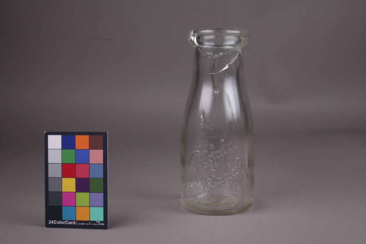 The same wide-necked glass bottle with the broken section reattached to the neck. The crack of the break is still visible.