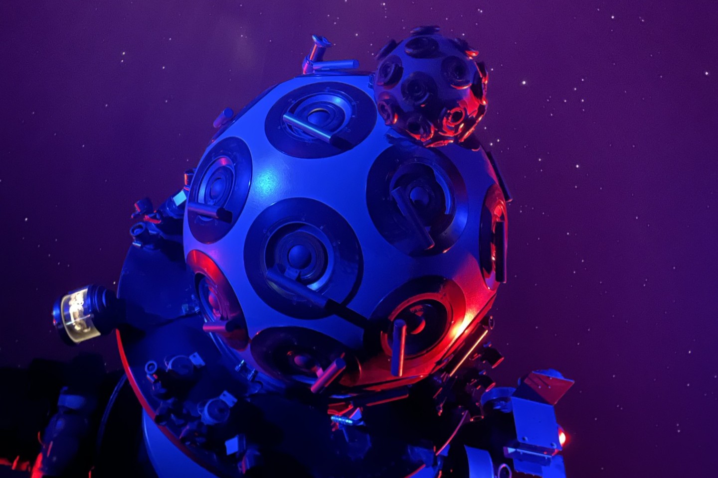 Close-up on the upper end of the planetarium's Zeiss Mark 5-S optomechanical star projector lit in blue hues