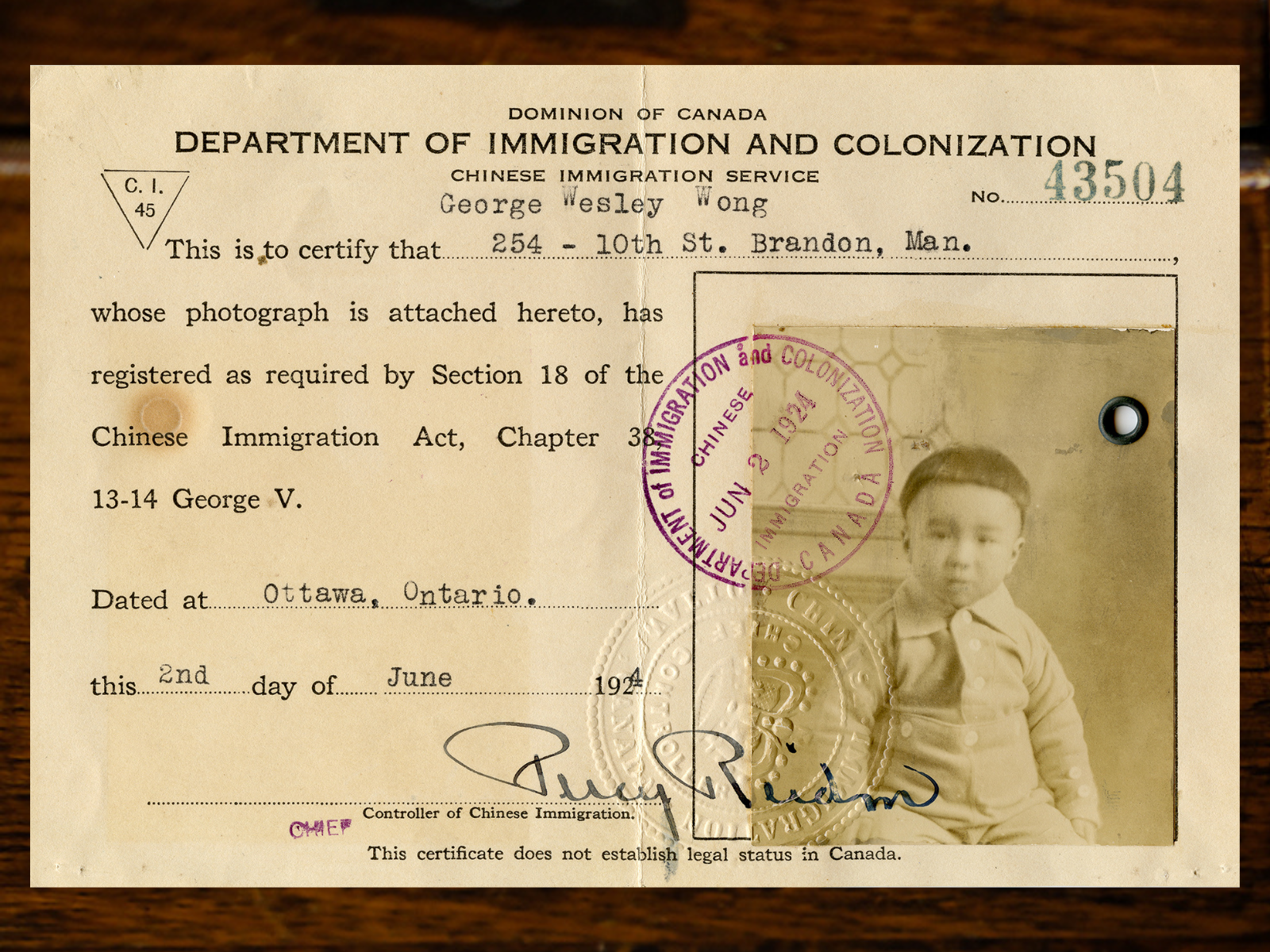 An immigration card issued from the Dominion of Canada Department of Immigration and Colonialization Chinese Immigration Service with an identification photograph of a small child, George Wesley Wong.