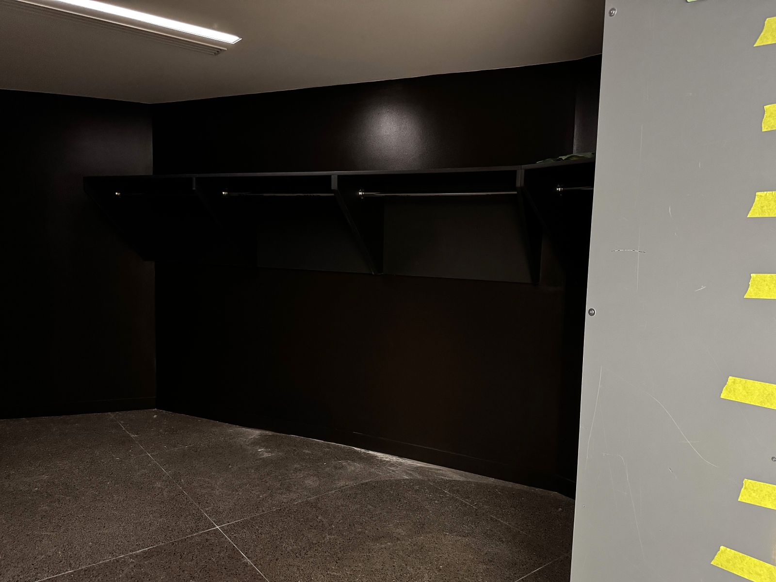Looking into a darkly painted room lined with upper shelves and hanger rods.
