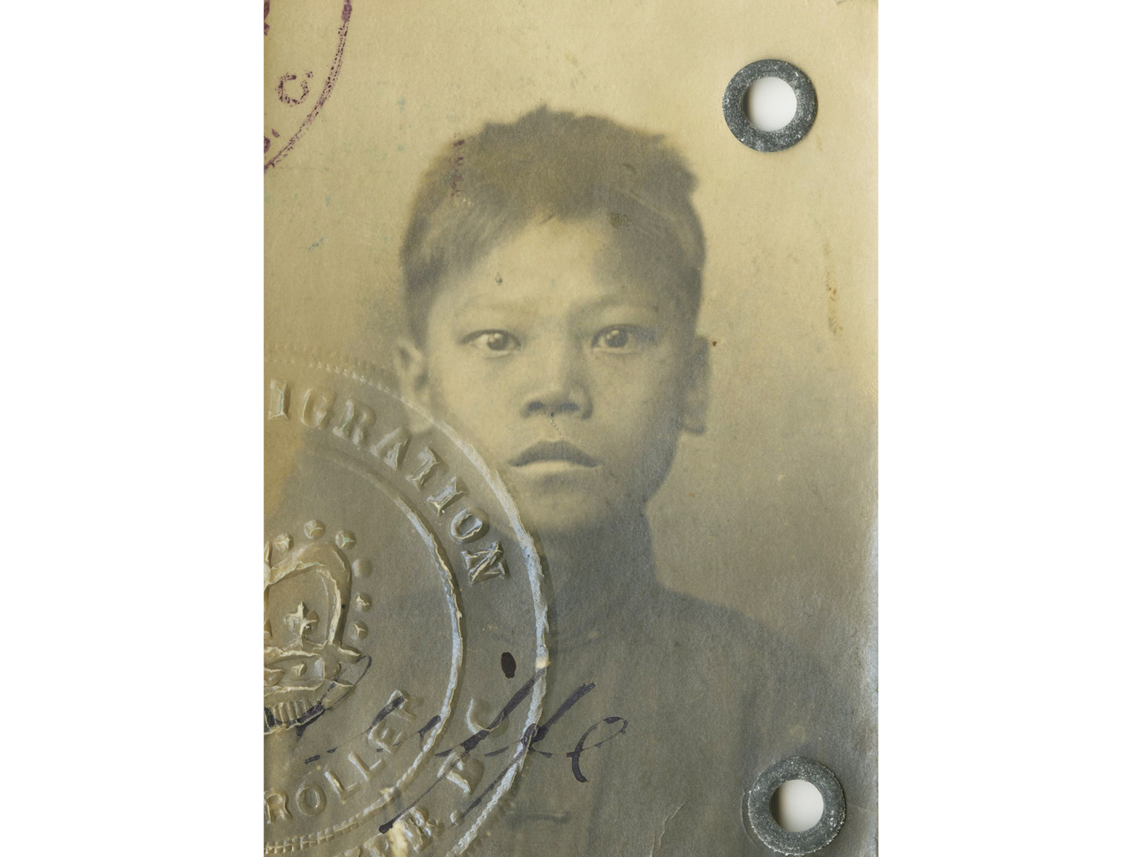 Sepia toned photograph of a somber faced child with part of an embossing stamp visible in the lower left corner.