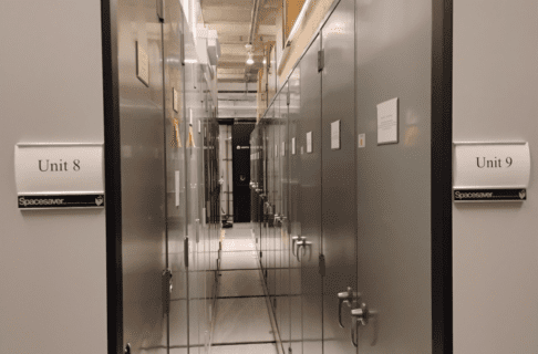 Looking down the aisle between two rolling units of storage cabinets. On the outer sides, closest to the camera, labels read "Unit 8" and "Unit 9".